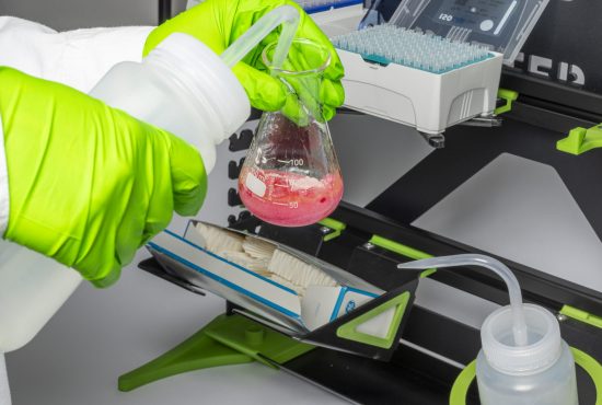 Ein Erlenmeyerkolben wird mit einem Spritzflasche gefüllt vor einem SmartRack